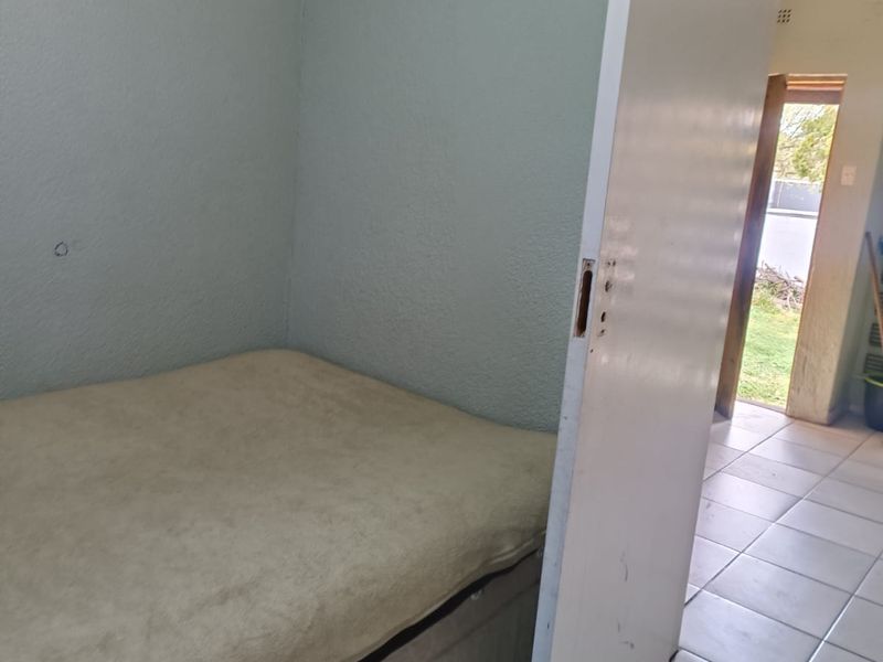 A bedroom featuring tiled flooring and a door requiring hardware replacement. The space shows signs of wear and would benefit from cosmetic updates.