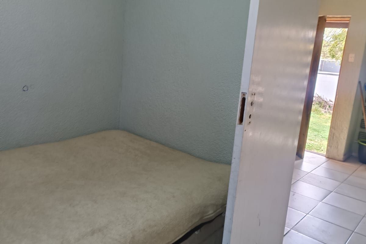 A bedroom featuring tiled flooring and a door requiring hardware replacement. The space shows signs of wear and would benefit from cosmetic updates.