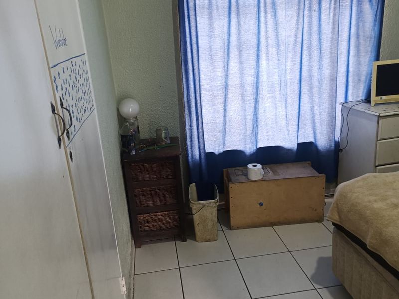 A bedroom featuring tiled flooring and a built-in cupboard, requiring cosmetic updates to improve the overall aesthetic and condition of the space.