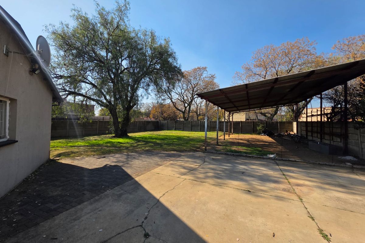 Spacious rear garden featuring a large concrete paved area, a covered outdoor shelter, and perimeter walling.