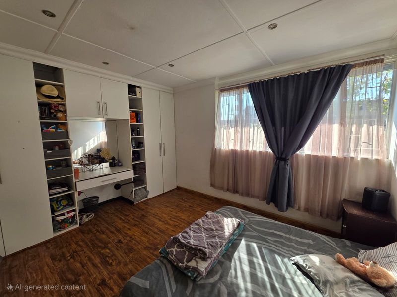A bedroom featuring built-in cabinetry with an integrated vanity desk, wood-look flooring, and a large window with curtains.