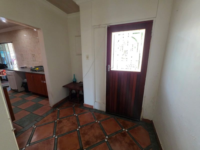 Entrance hall featuring tiled flooring and a solid wood door with decorative glass panel, providing direct access to the adjacent kitchen area.