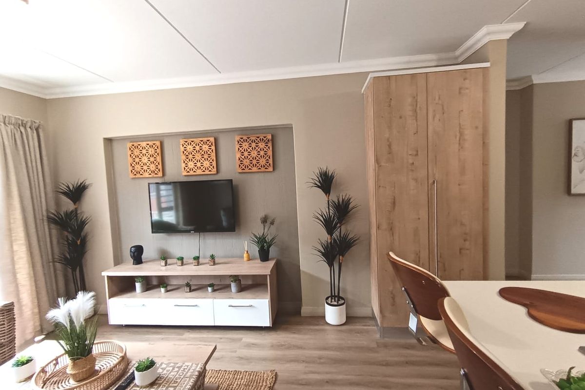 A well-maintained living area featuring a built-in media alcove, wood-look laminate flooring, and a tall integrated storage cabinet.