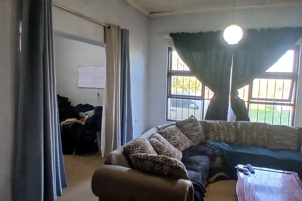 A living room area featuring tiled flooring, security bars on the windows, and a pendant light fixture.