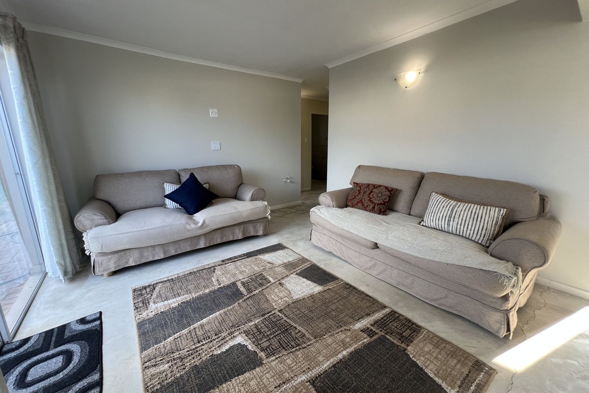 A bright living room featuring neutral walls, tiled flooring, and sliding glass doors providing access to the outdoor area.