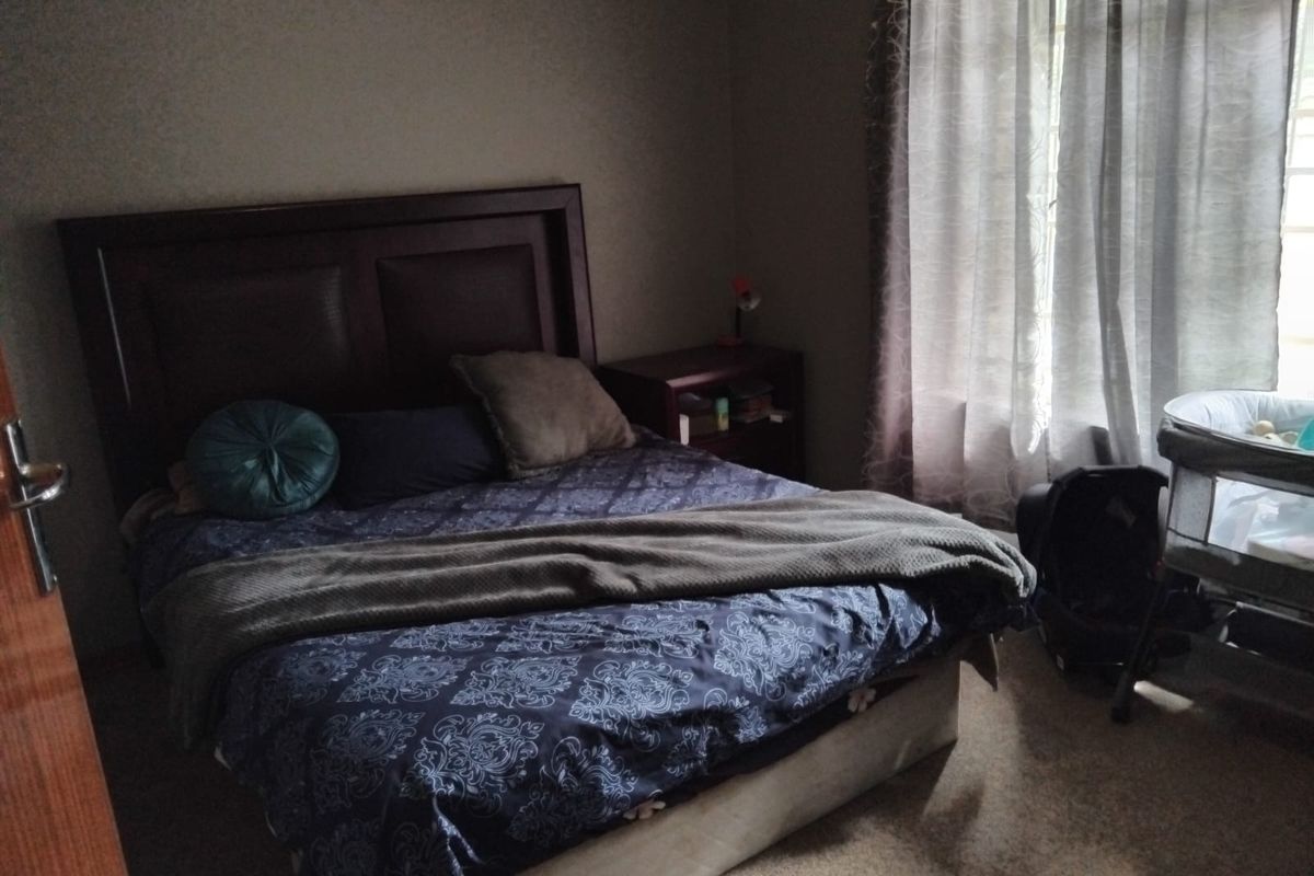 A bedroom featuring carpeted flooring and a window with curtains, providing natural light to the space.