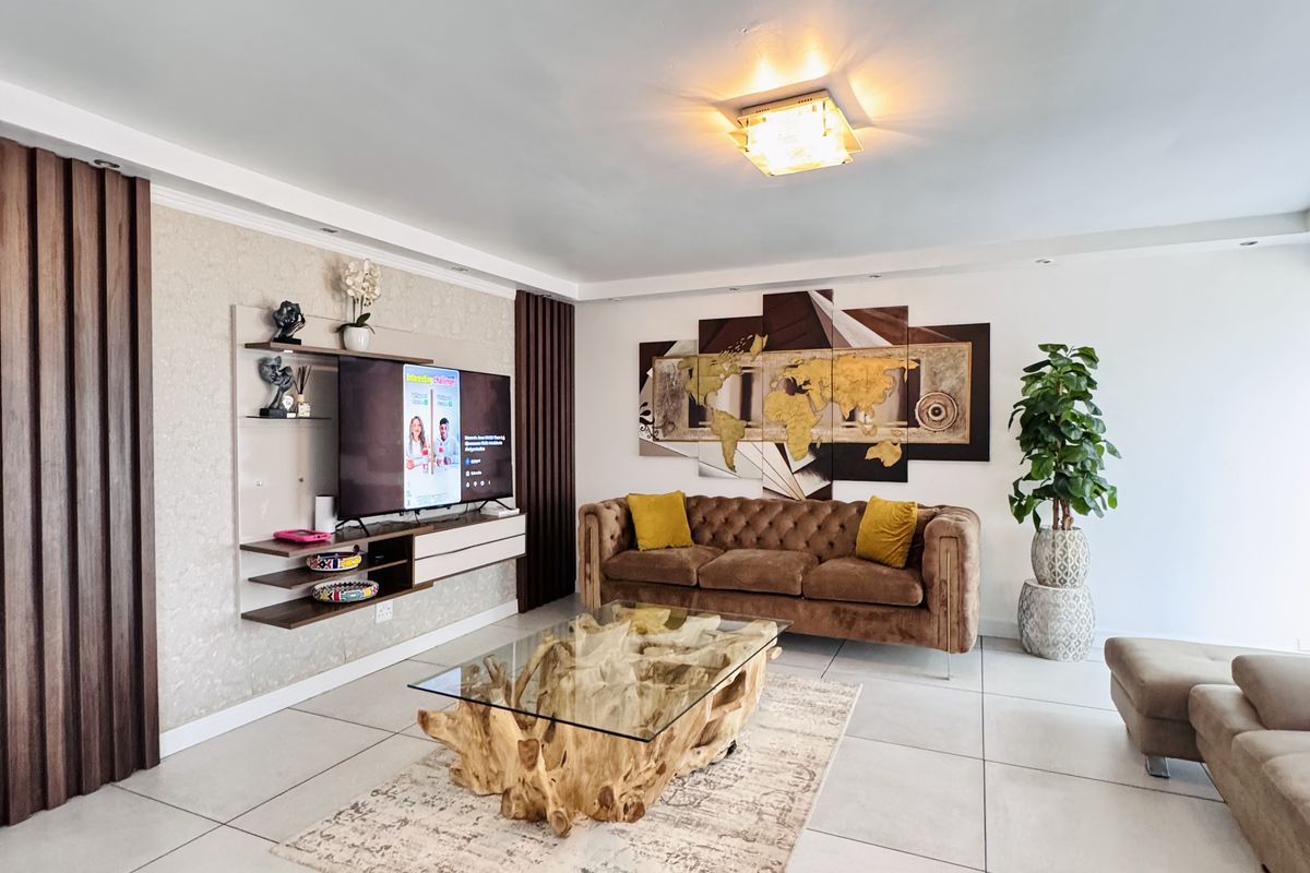 A modern living room featuring large format floor tiles, decorative wall paneling, and a built-in media console unit.