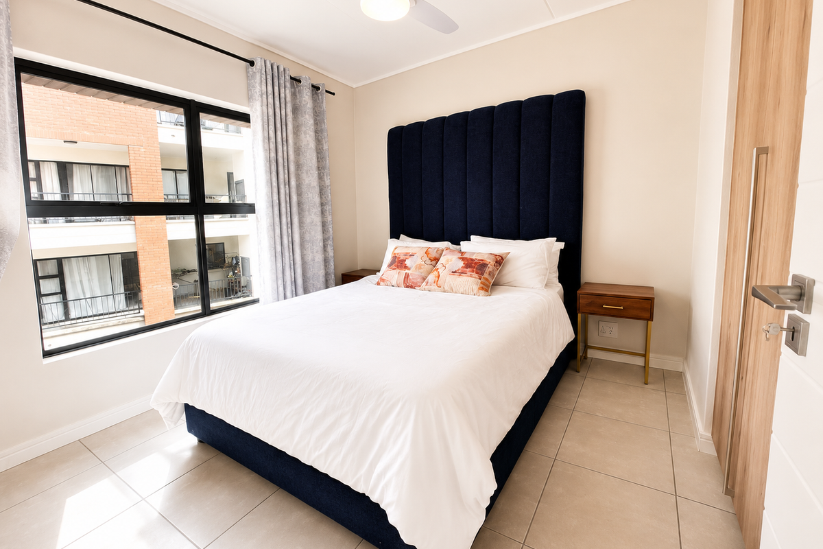 A bright and modern bedroom featuring large windows, tiled flooring, a ceiling fan, and built-in wooden cabinetry.