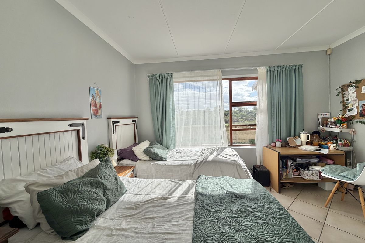 A spacious bedroom featuring tiled flooring, large windows with natural light, and neutral wall finishes, providing a comfortable living space.