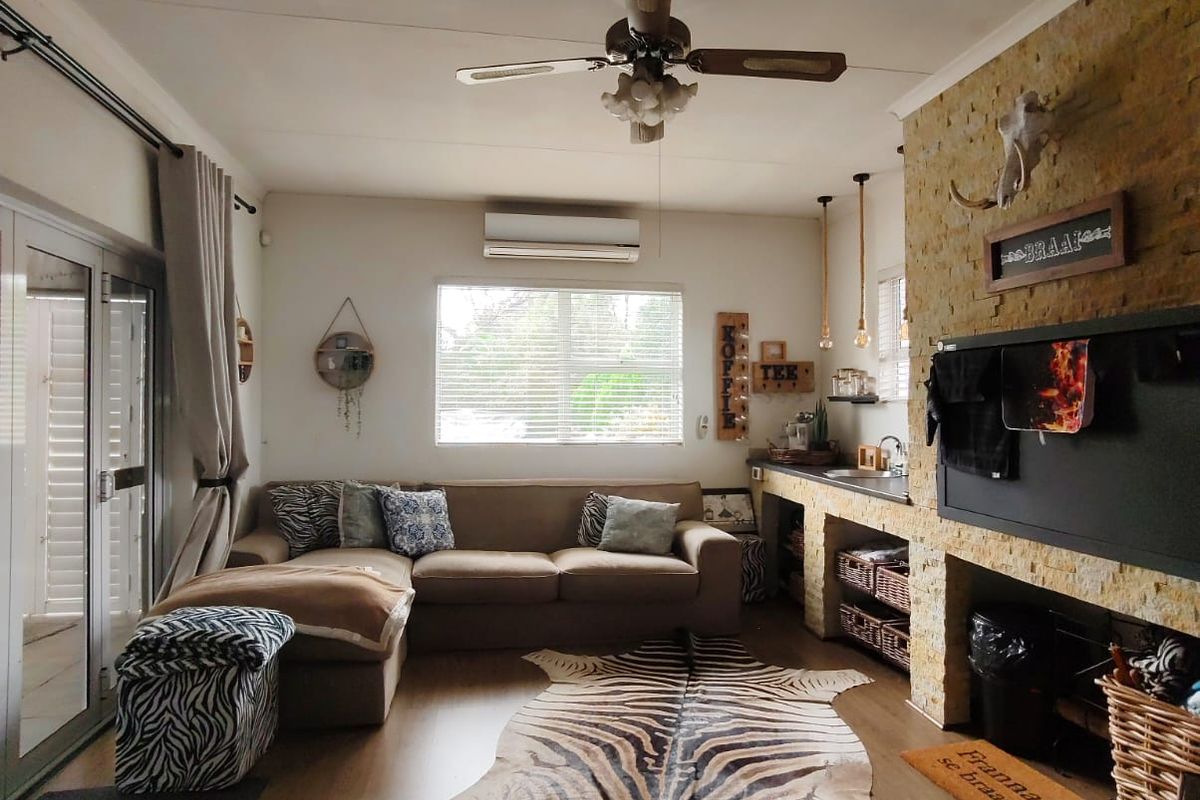 A cozy living area featuring a stone-clad feature wall with a built-in bar counter, ceiling fan, air conditioning unit, and sliding glass doors.