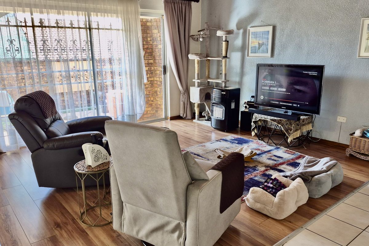 A comfortable living room featuring wood-look laminate flooring and large sliding glass doors that provide access to an outdoor patio area.