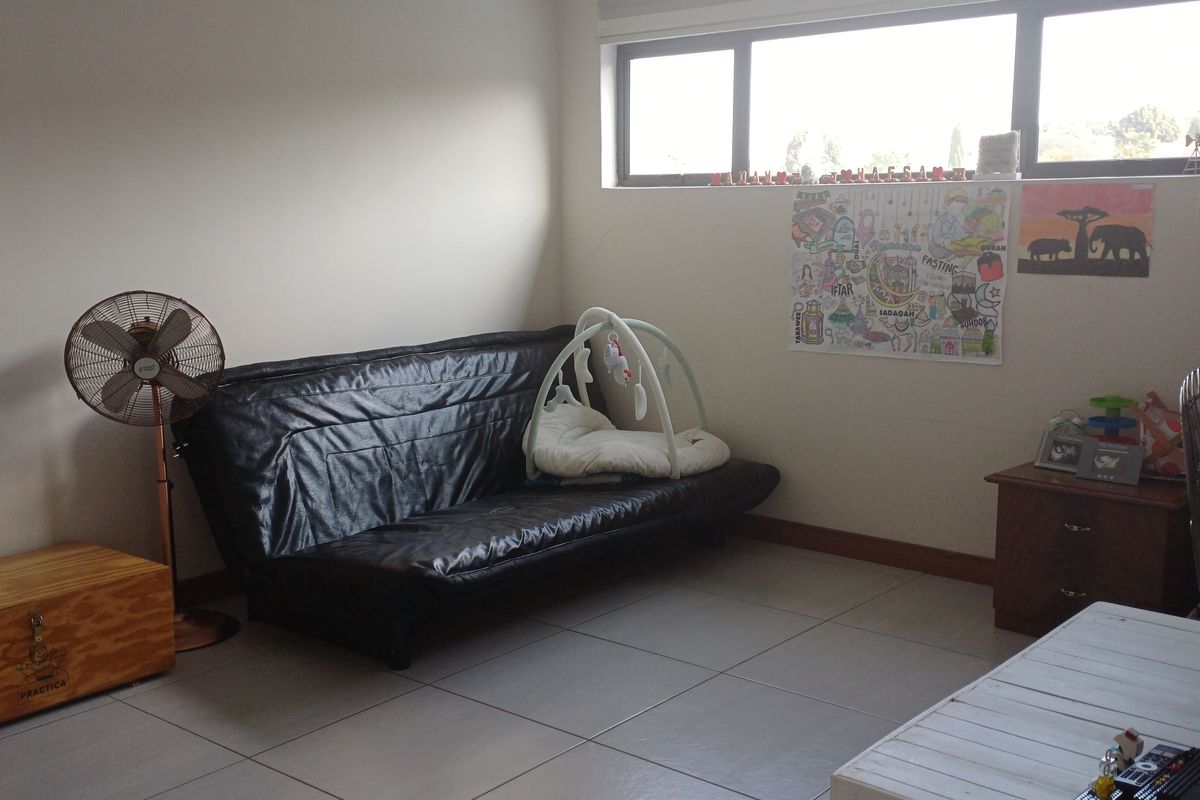 A bedroom featuring tiled flooring and a large horizontal window, providing natural light to the space.