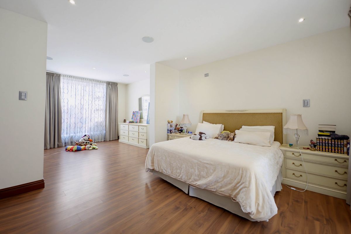 Spacious bedroom featuring laminate flooring, recessed downlighting, and large windows with curtain tracks, offering a bright and comfortable living space.