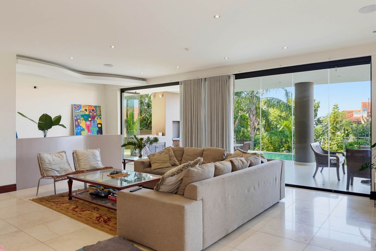 Spacious open-plan living area featuring large format floor tiles, recessed lighting, and expansive sliding glass doors that provide seamless access to the outdoor patio.