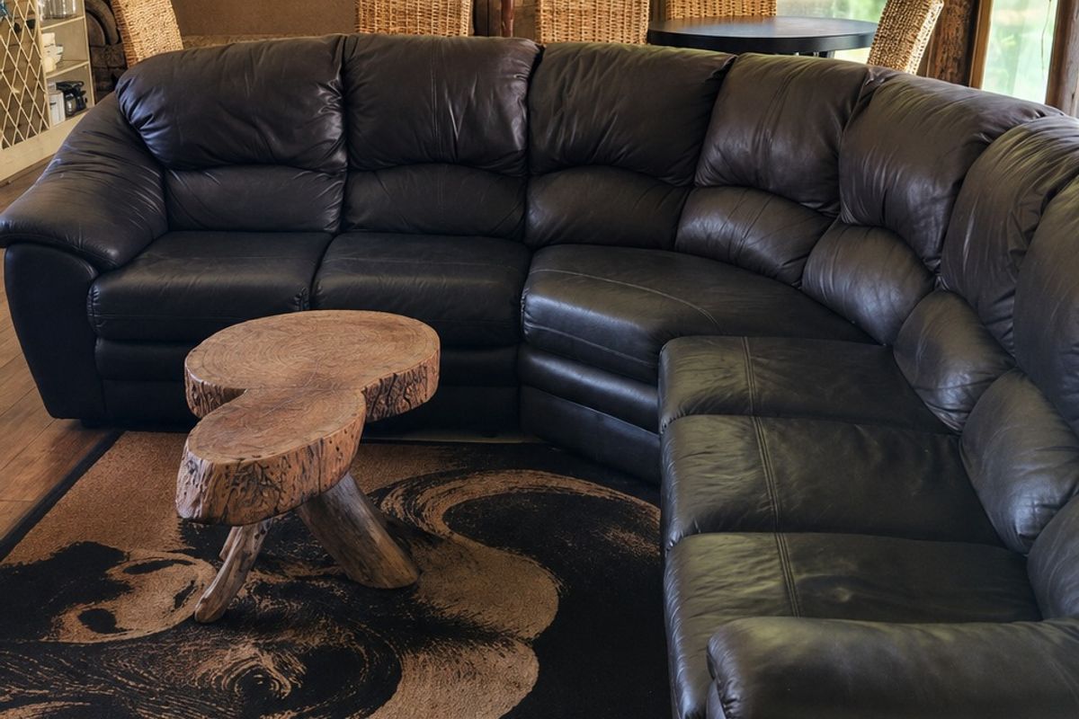Spacious living area featuring a rustic thatched roof, exposed brick walls, and timber flooring, creating a warm and character-filled atmosphere.