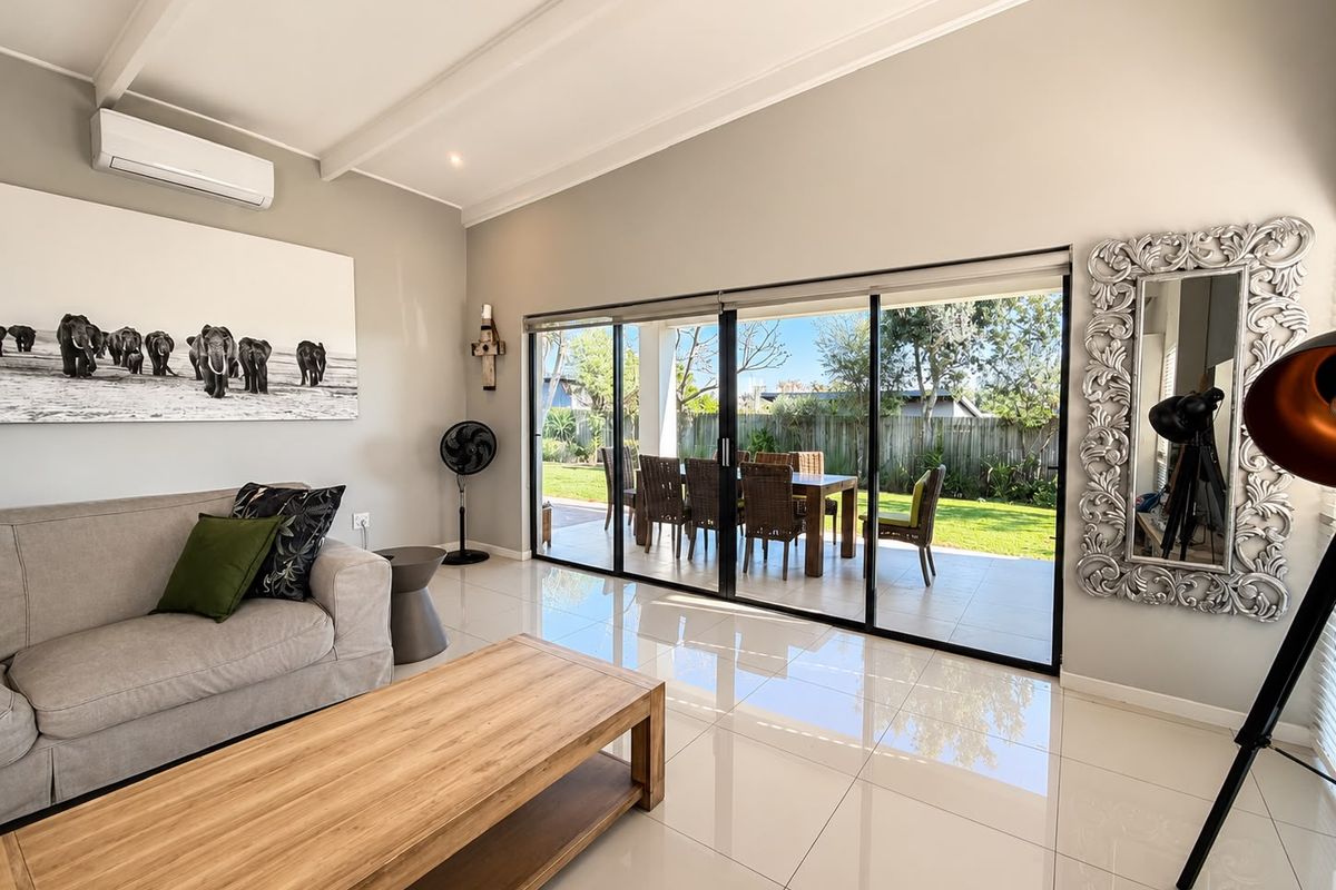 Bright living room featuring large sliding glass doors that open onto a patio, polished tiled floors, and a split-system air conditioner.