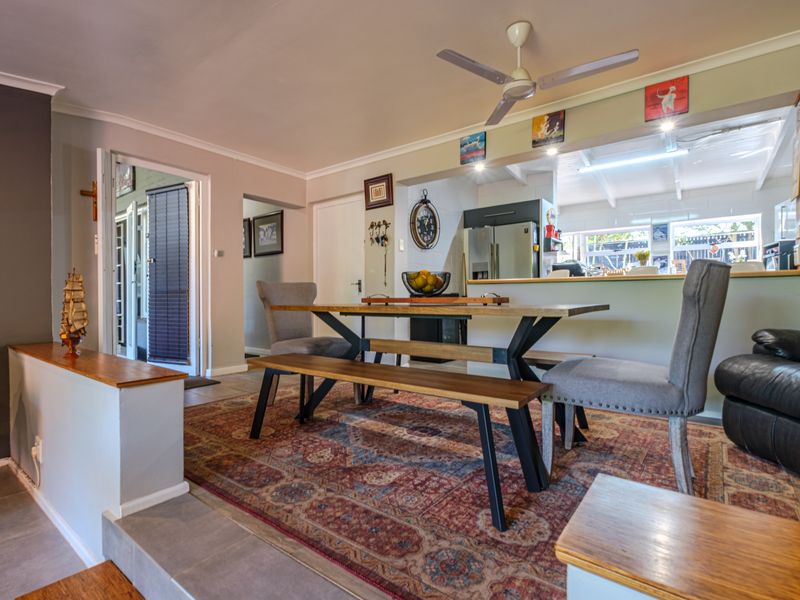 Open plan dining area featuring a raised floor level, ceiling fan, and a serving hatch opening into the adjacent kitchen space.