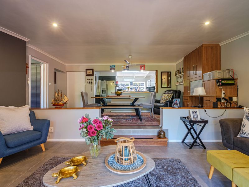 An open-plan living and dining area featuring tiled flooring, recessed ceiling lighting, and a split-level layout connecting the lounge to the dining space.