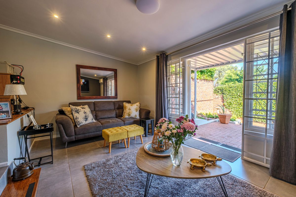 A comfortable living room featuring large glass doors that open onto a paved patio area, providing seamless indoor-outdoor flow and natural light.