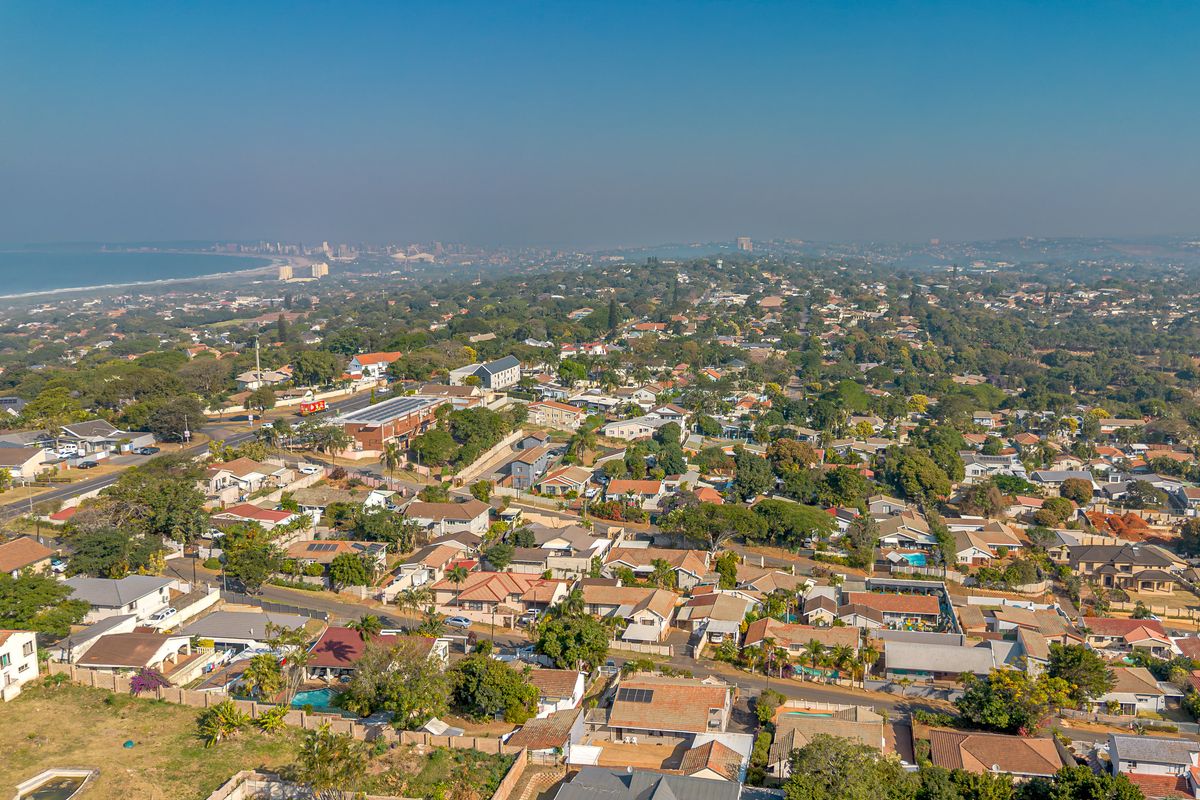 An elevated aerial view showcasing the surrounding residential neighborhood, local infrastructure, and coastal landscape.