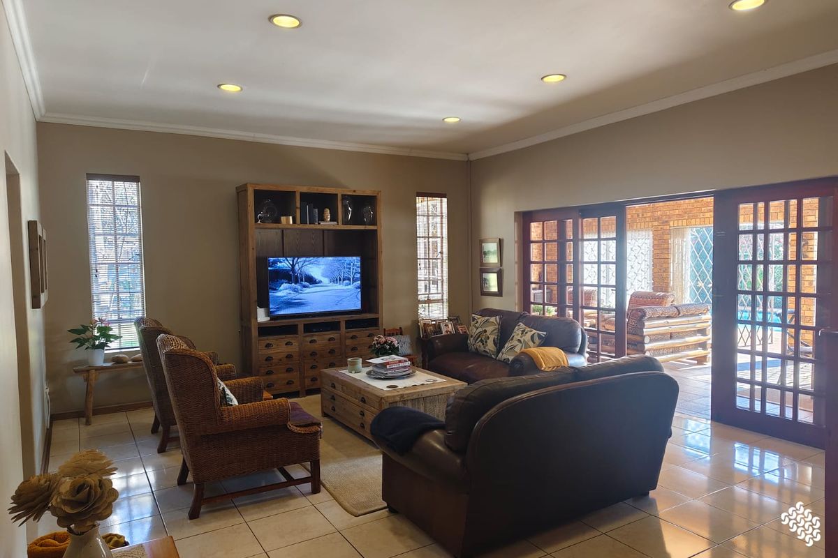 Spacious living room featuring tiled flooring, recessed ceiling lighting, and large glass sliding doors providing seamless access to the outdoor patio area.