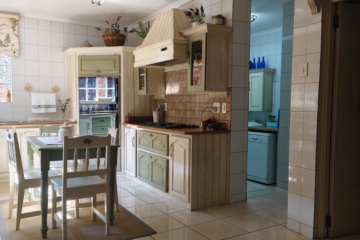 A traditional kitchen featuring built-in cabinetry, a tiled backsplash, and an integrated extractor fan, with an adjacent scullery area visible.