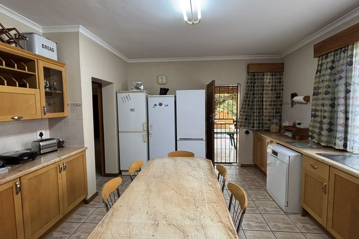 A functional kitchen featuring wooden cabinetry, tiled flooring, and direct access to an outdoor area through a security gate.