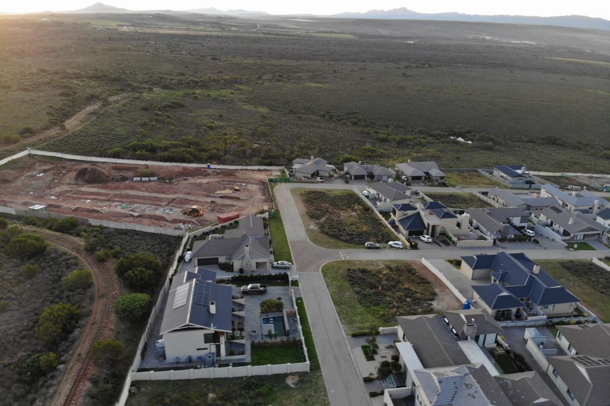 Aerial view of a residential estate showing established homes and an adjacent plot of vacant land prepared for development.