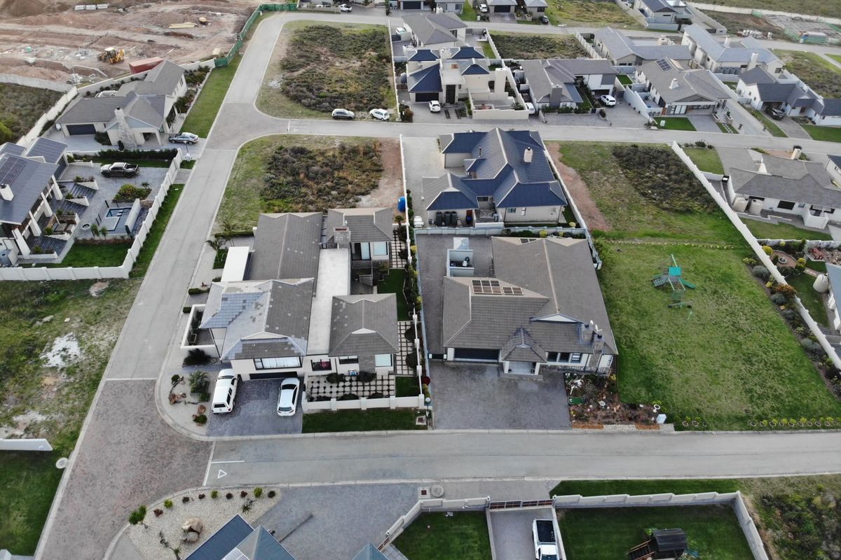 Aerial view of a residential estate featuring modern detached homes with tiled roofs, paved driveways, and landscaped garden plots.