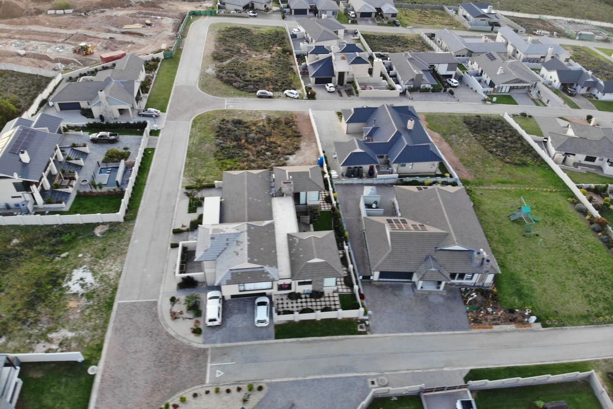 Aerial view of a residential estate featuring multiple detached homes, paved streets, and landscaped plots within a suburban development.
