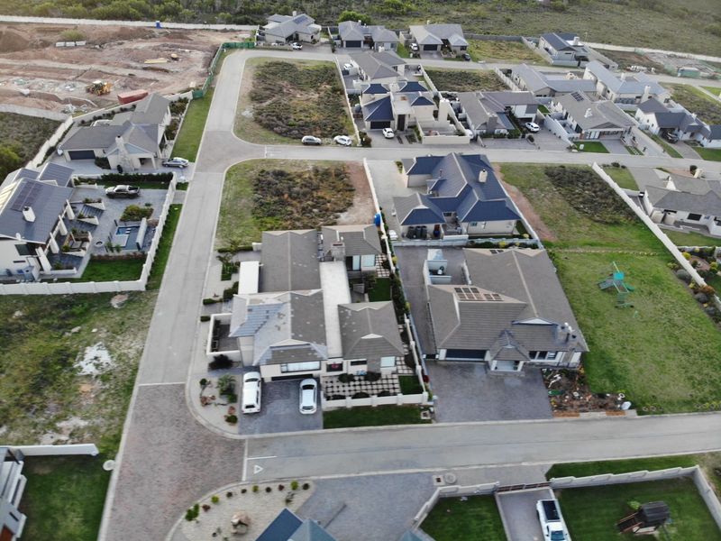 Aerial view of a residential estate featuring multiple detached homes, paved streets, and landscaped plots within a suburban development.