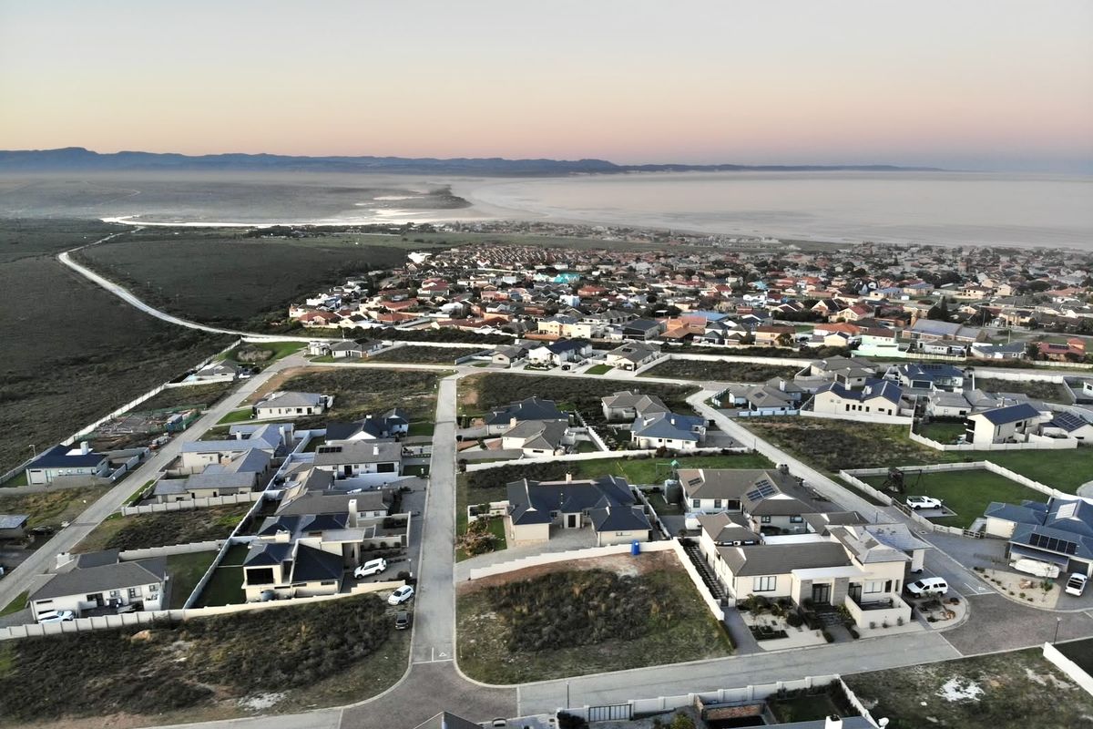 An aerial view of a residential neighborhood and surrounding coastal landscape, showcasing the property's location within the established community.