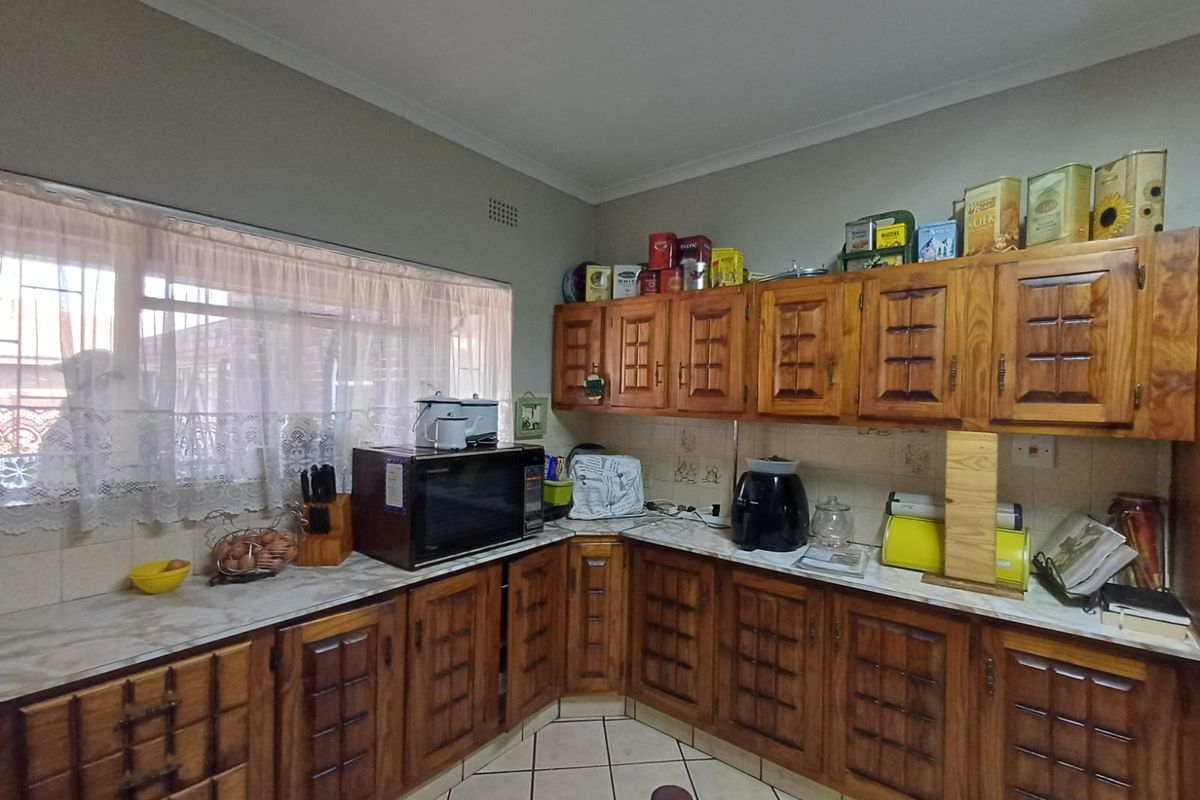 A functional kitchen featuring traditional wooden cabinetry, tiled flooring, and ample counter space, offering a classic aesthetic with potential for modern updates.