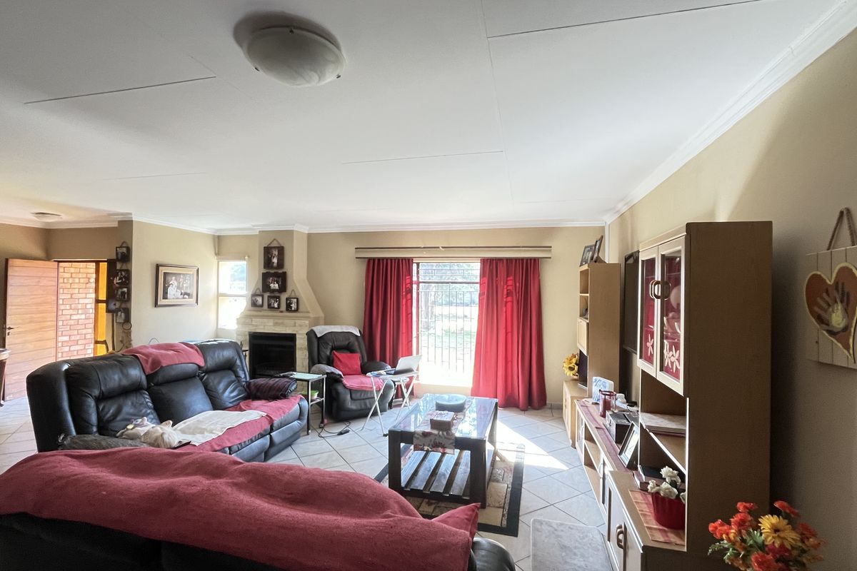 Spacious living room featuring a built-in fireplace, tiled flooring, and large windows with natural light, providing a comfortable and functional family living space.