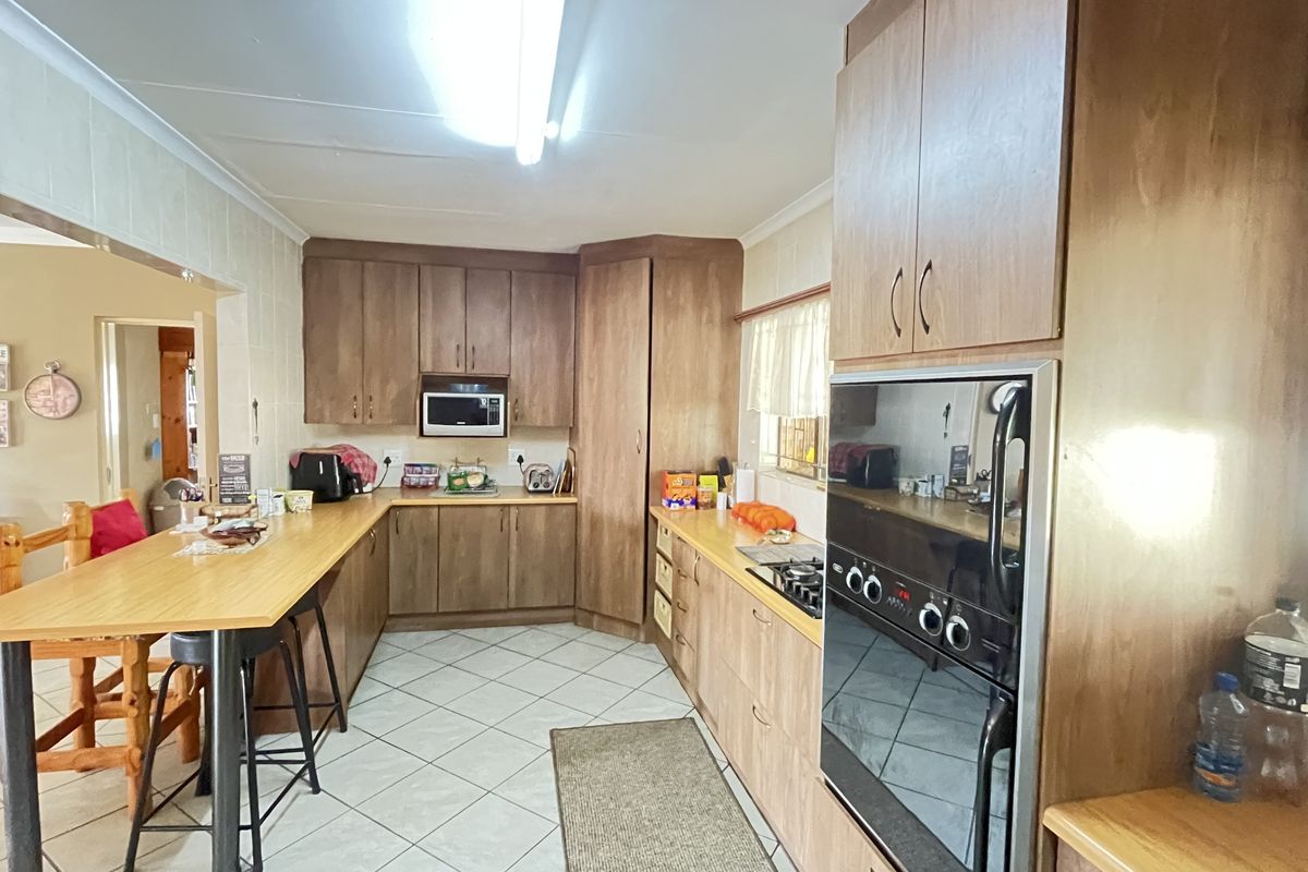 A functional kitchen featuring wood-look cabinetry, a built-in oven, a gas hob, and an integrated breakfast bar counter.