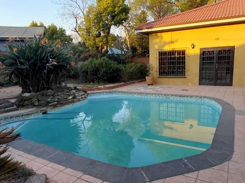 Outdoor pool area featuring a paved patio, established garden landscaping, and direct access to the home via sliding doors.