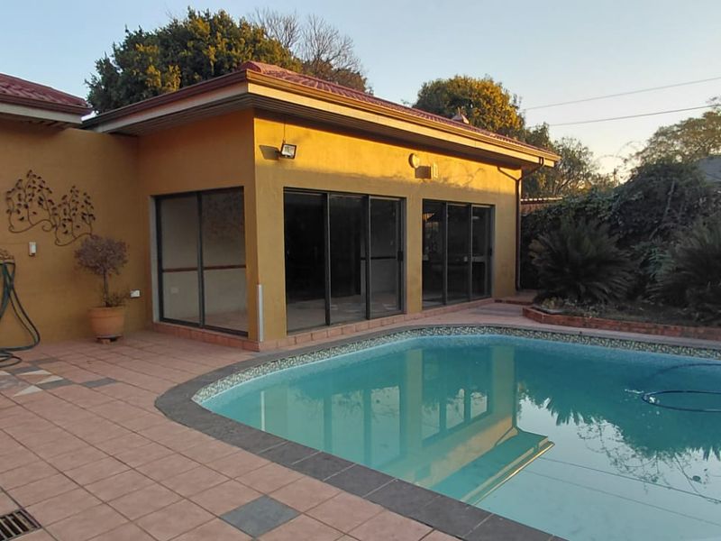 Outdoor entertainment area featuring a swimming pool, tiled patio, and direct access to the home through large sliding glass doors.