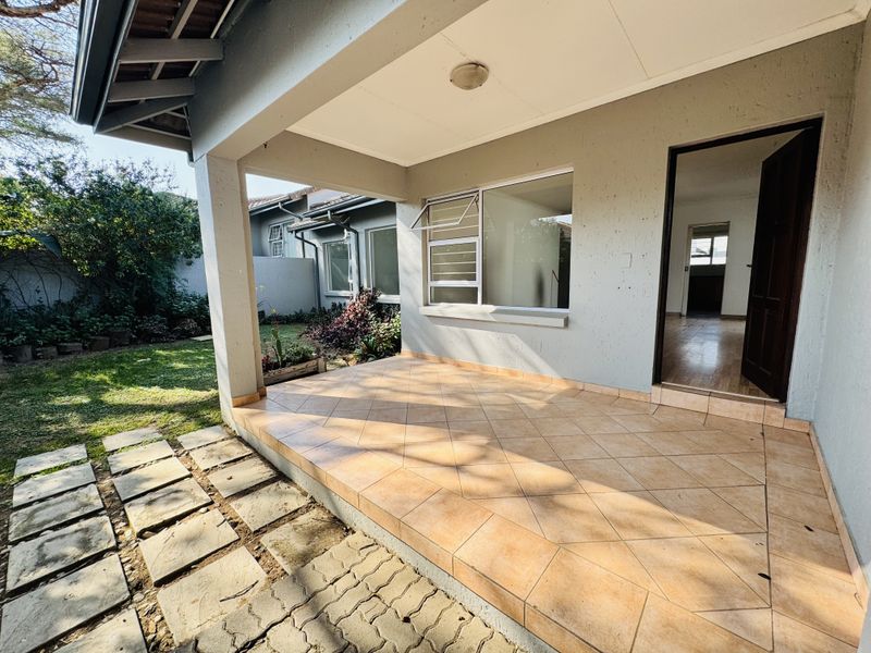 A covered patio area with tiled flooring, providing direct access to the interior living space and overlooking the private garden.