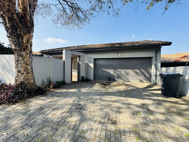 Front exterior view of the townhouse featuring a paved driveway, single garage with roller door, and a private pedestrian entrance.