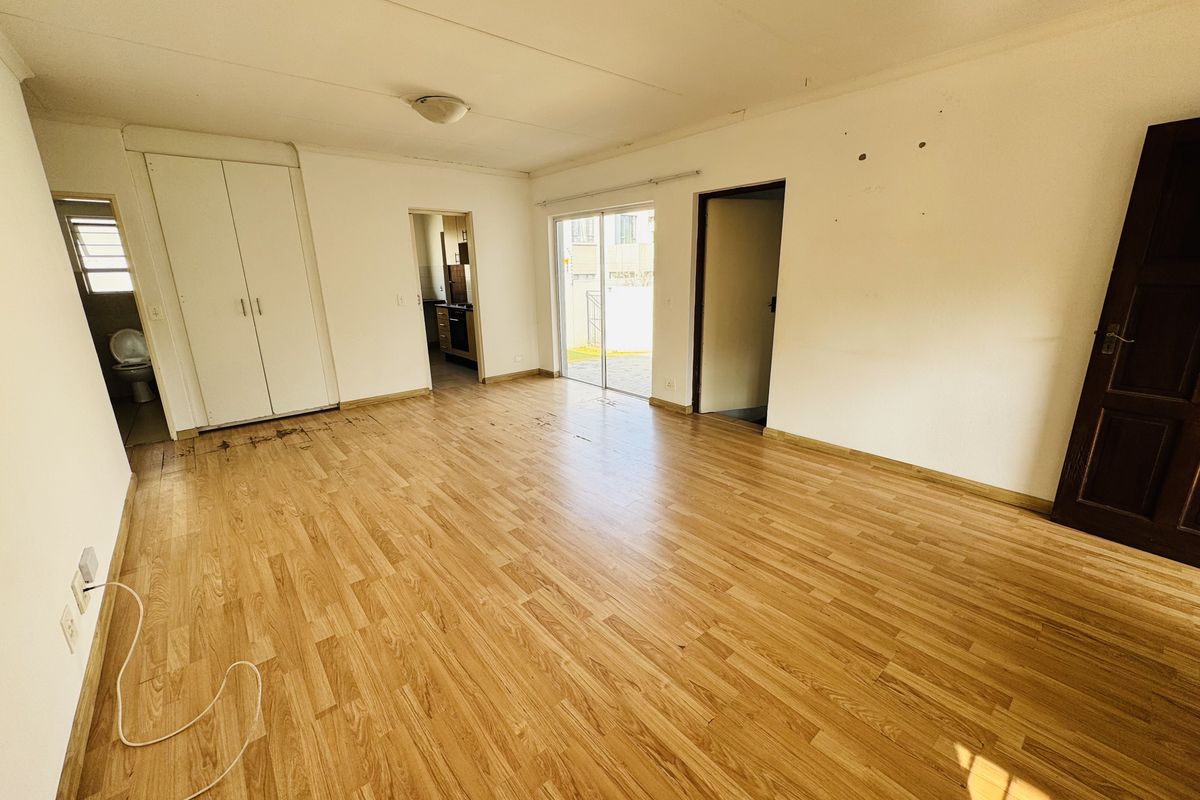 An empty living area featuring wood-look laminate flooring, built-in closet storage, and sliding glass doors leading to an outdoor space.