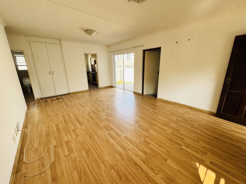 An empty living area featuring wood-look laminate flooring, built-in closet storage, and sliding glass doors leading to an outdoor space.