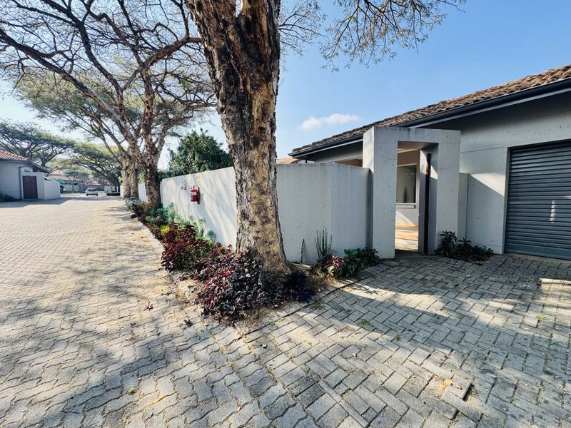 Street-level view of the townhouse exterior, featuring a paved driveway, secure boundary wall, and private entrance gate.