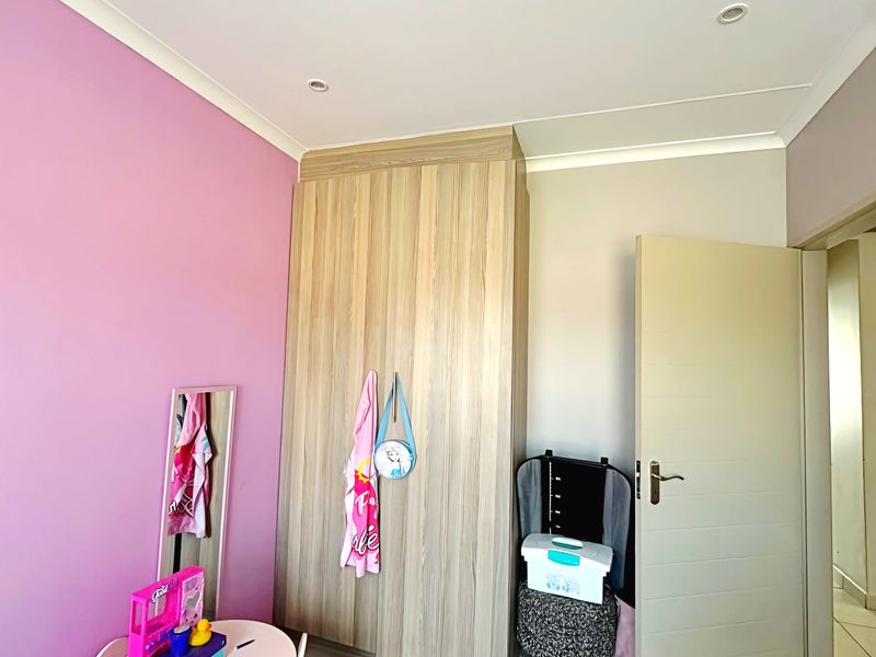A bedroom featuring tiled flooring, recessed downlighting, and a built-in wood-grain wardrobe, currently styled as a child's room.