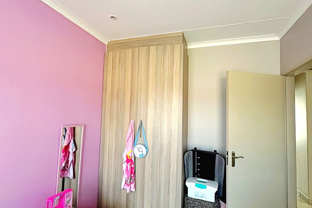 A bedroom featuring tiled flooring, recessed downlighting, and a built-in wood-grain wardrobe, currently styled as a child's room.