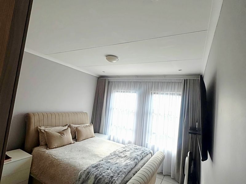 A well-maintained bedroom featuring tiled flooring, recessed ceiling lighting, and built-in wardrobe storage with neutral wall finishes.