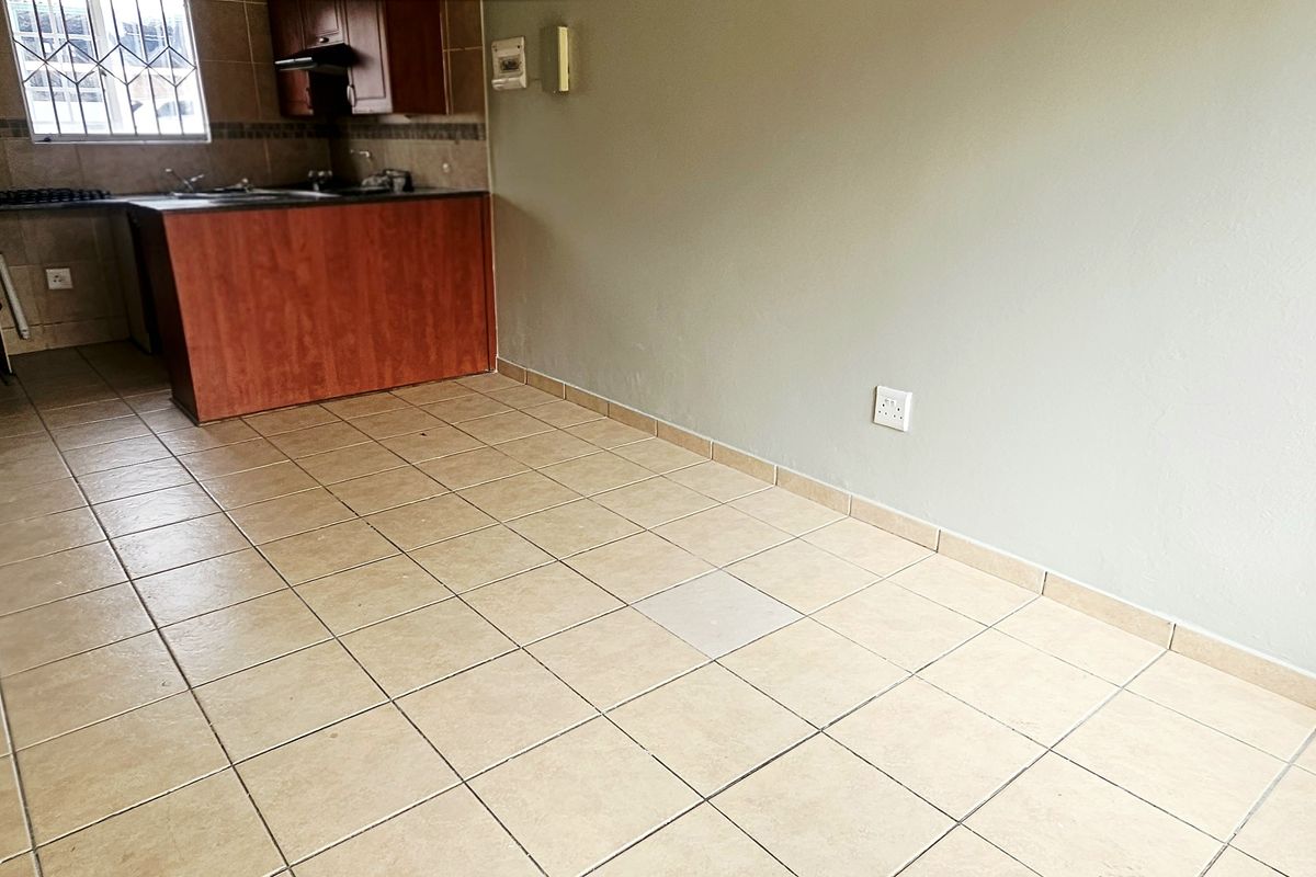 Open plan living area featuring tiled flooring and a compact kitchen with built-in cabinetry and sink.