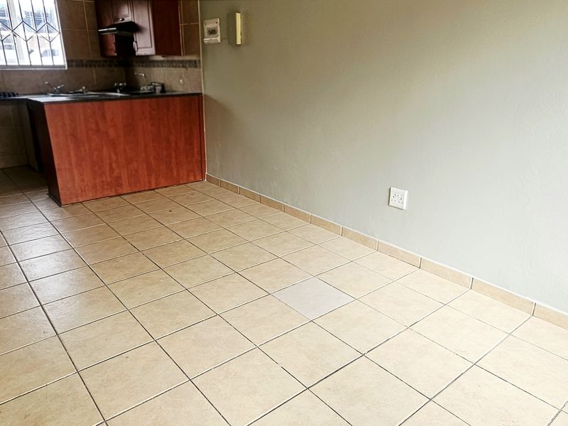 Open plan living area featuring tiled flooring and a compact kitchen with built-in cabinetry and sink.