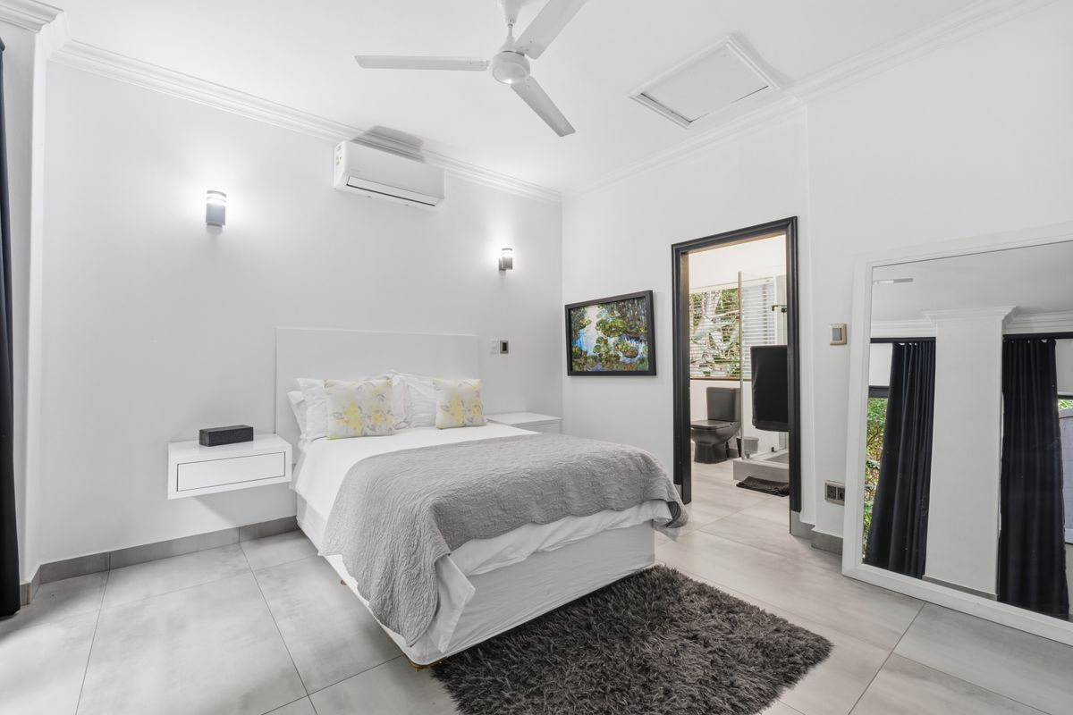 A bright, modern bedroom featuring tiled floors, a ceiling fan, split system air conditioning, and direct access to an en-suite bathroom.