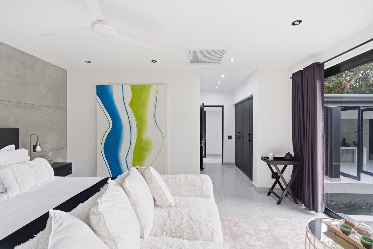 Modern bedroom featuring a concrete accent wall, built-in cabinetry, recessed lighting, and direct access to an outdoor area through sliding glass doors.