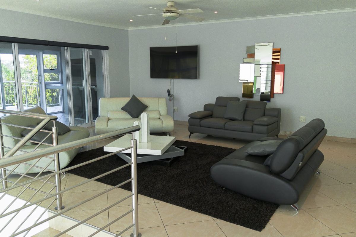Spacious living area featuring tiled flooring, a ceiling fan, and large sliding glass doors that open onto an outdoor balcony.